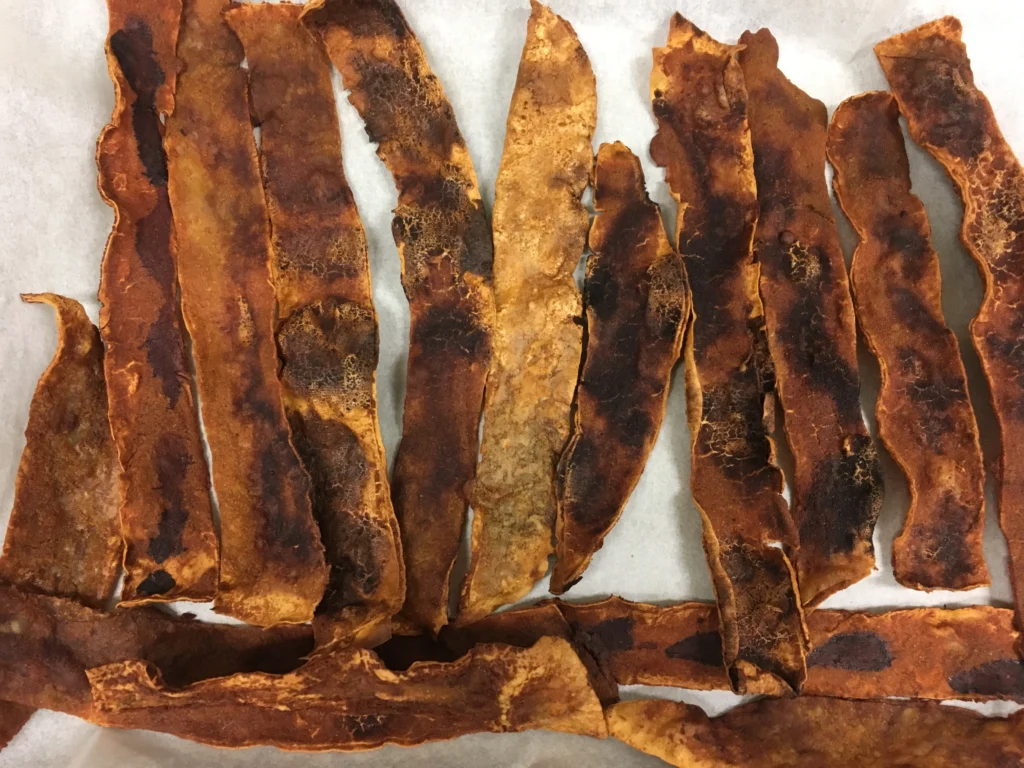 Crispy brown vegan bacon strips on parchment.