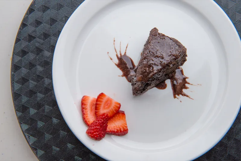 Chocolate cake with strawberries on white plate.