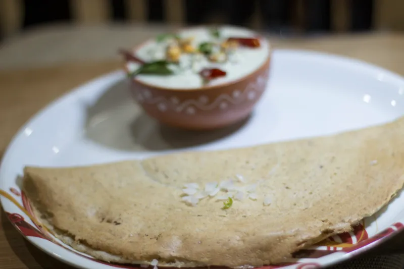Dosa with chutney on a white plate.