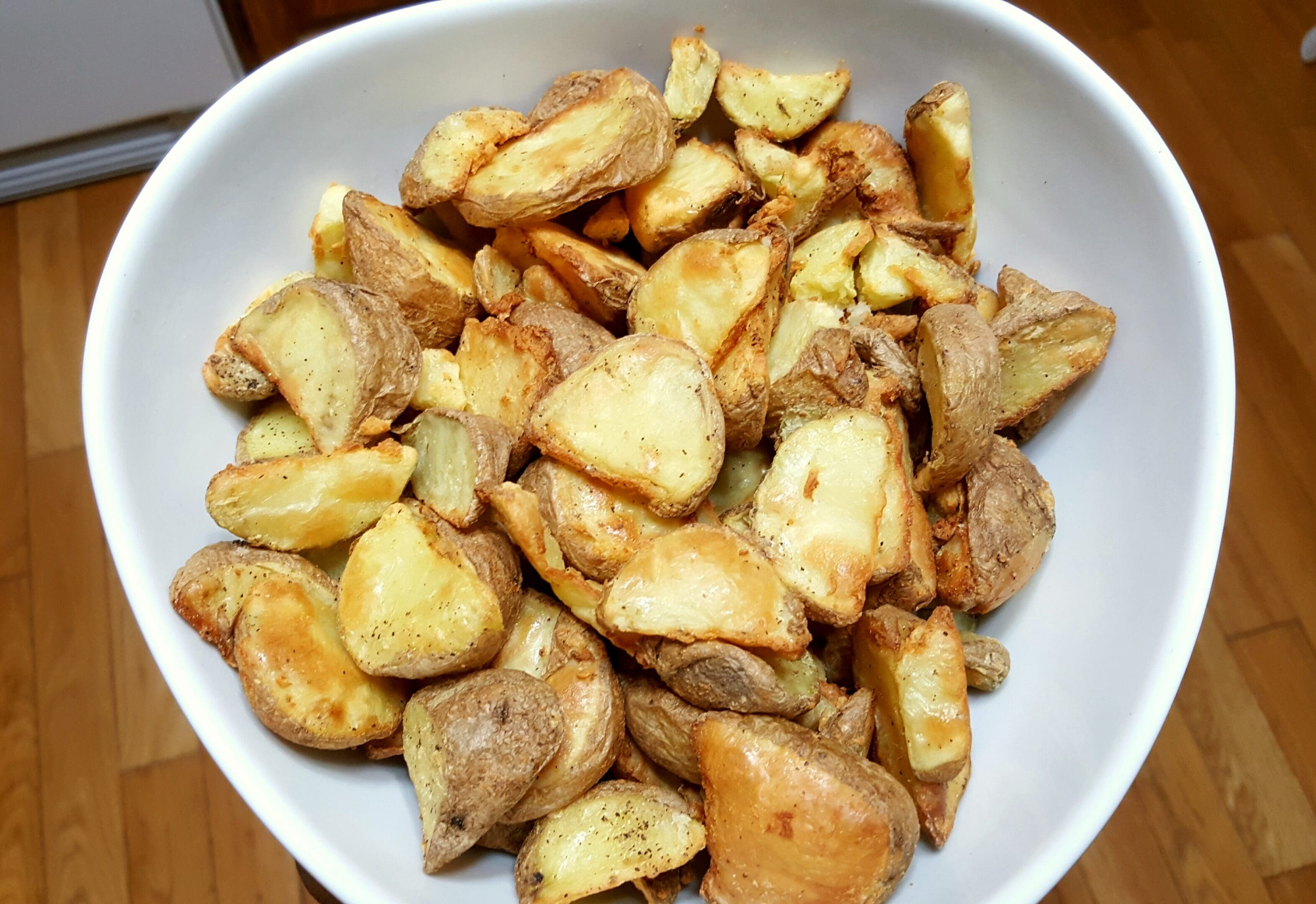 Bowl of roasted potato wedges on table.